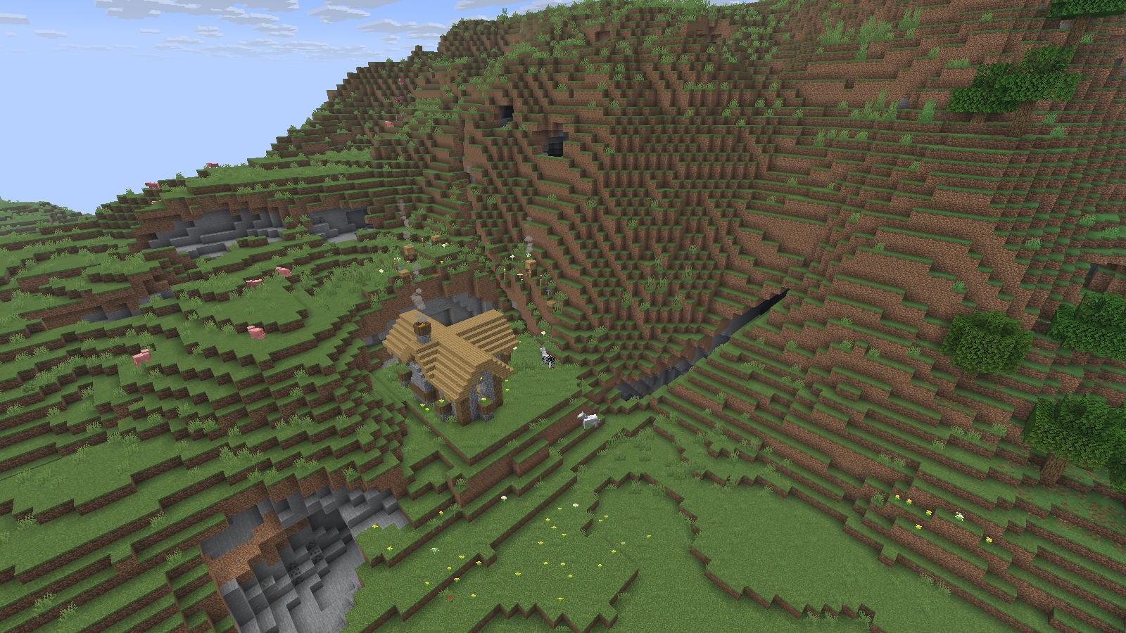 A small farmstead occupies a grassy shelf below a steep hillside, with exposed stone and deep cuts nearby.