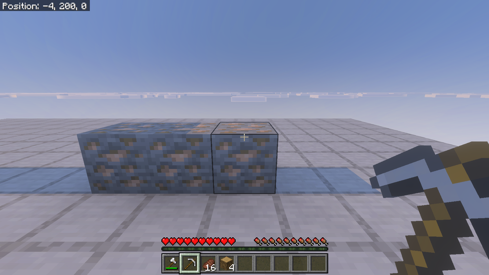 Three iron-ore blocks on the test platform before mining, with an iron pickaxe selected.