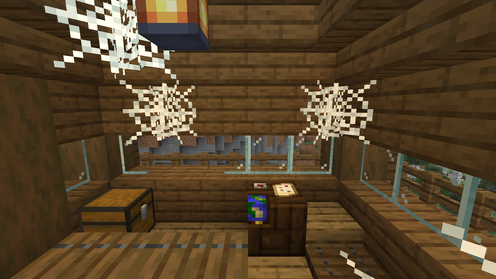 Detail with context: the firetower’s chest and cartography table sit beneath windows, a lantern and cobwebs.