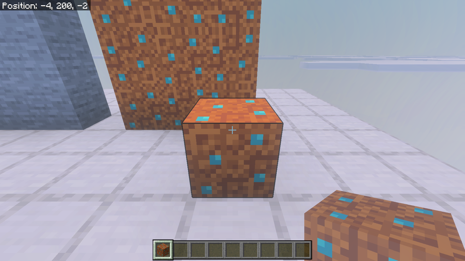 Native close view of a placed dirt block showing turquoise pebbles on its top and side faces.