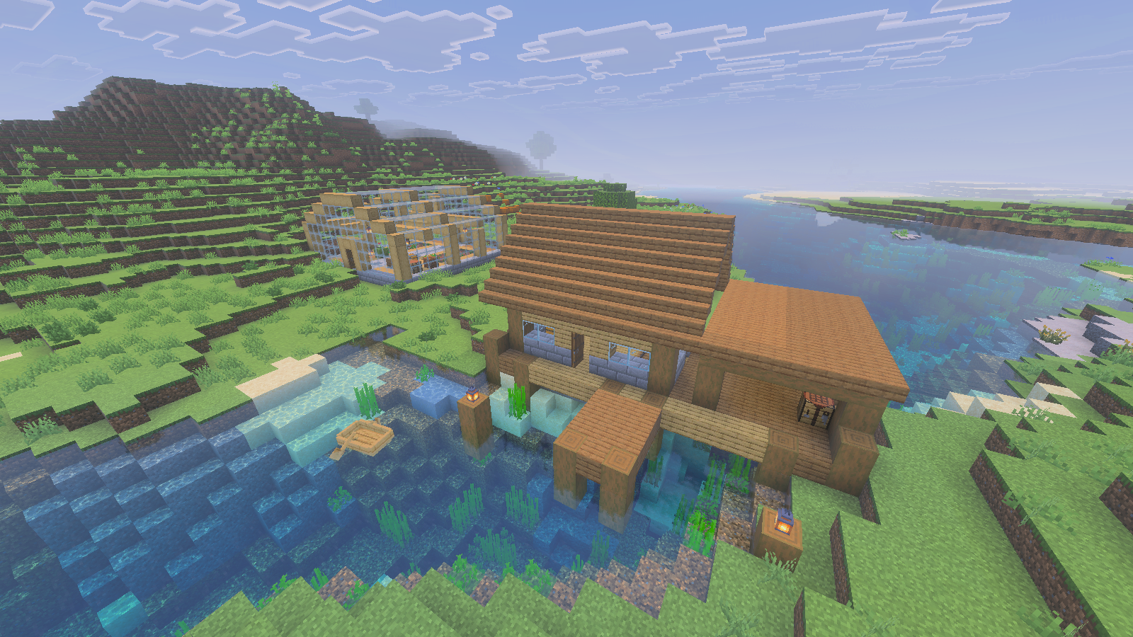 Timber warehouse, covered loading bay and wooden pier beside a river, with a separate greenhouse in the background.