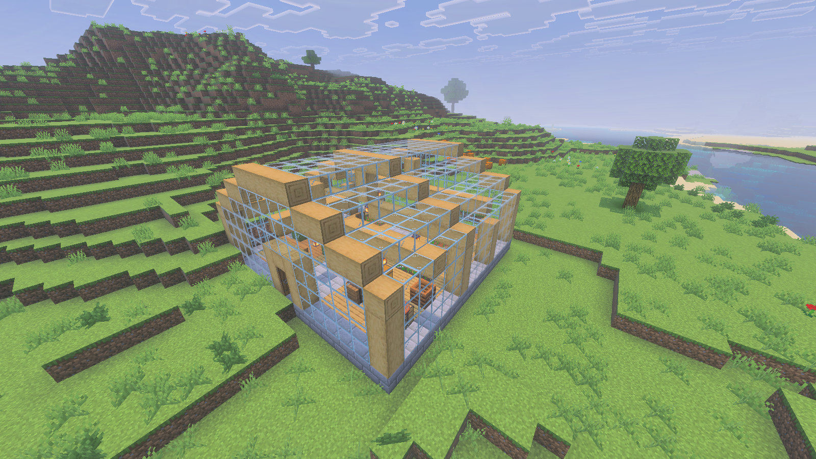 Glass-and-oak greenhouse on a riverbank, with its planted courts and open courtyard visible.