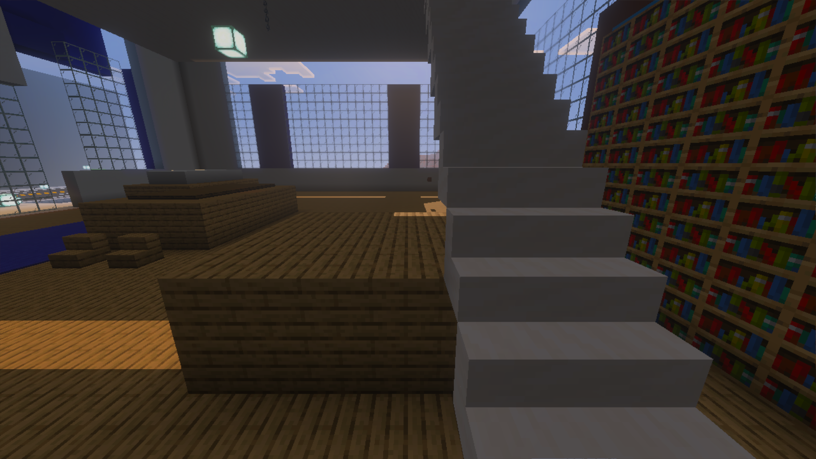 An HQ interior with wooden platforms, bookshelves, white stairs and tall glass walls.