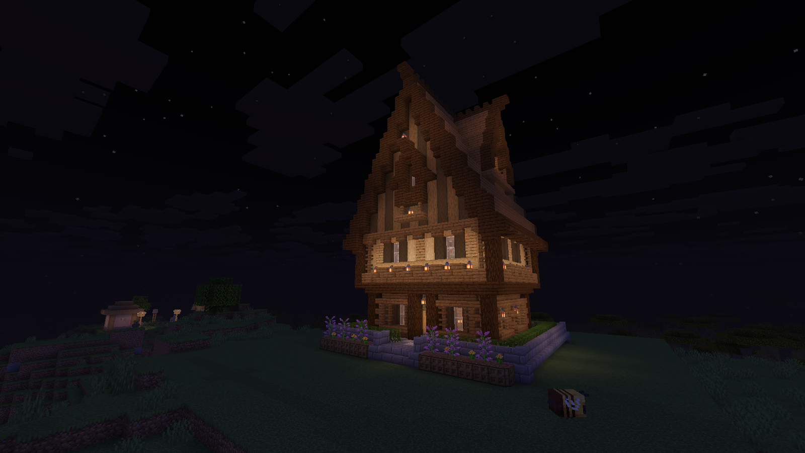 Warm lantern light around a tall wooden house at night with Miniature Shader 2.19.